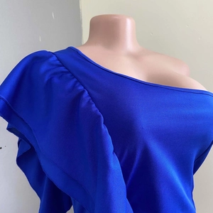 Detailed view of the layered ruffles and textured blue knit fabric on the one-shoulder dress
