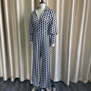 Detail view of houndstooth print jumpsuit featuring lantern sleeves and wide leg trousers