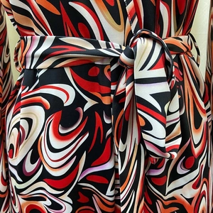 Detail of waist tie and vibrant retro swirl pattern on smooth African print jumpsuit