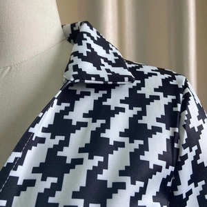 Close-up of black and white houndstooth jumpsuit with zipper detail and high-waist design