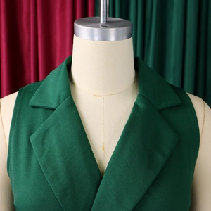 Detail of dark green sleeveless vest with notched lapel and smooth fabric texture