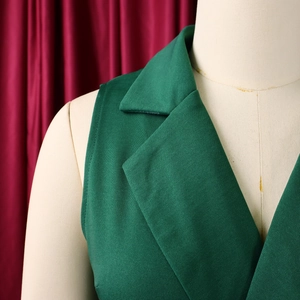 Detail of emerald green sleeveless jumpsuit featuring a sharp suit collar and clean stitching