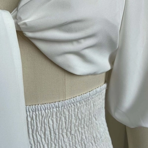 Detail of white two-piece set featuring smocked waist and pleated puff sleeve texture