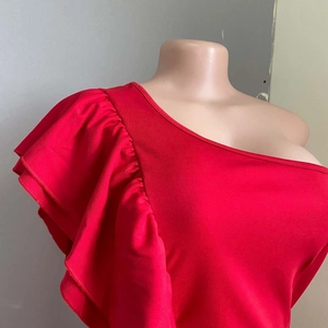 Close-up of red one-shoulder dress with dramatic ruffle sleeve and sleek fabric