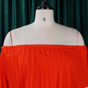 Détail du haut orange à épaules dénudées avec encolure élastique et texture plissée fine