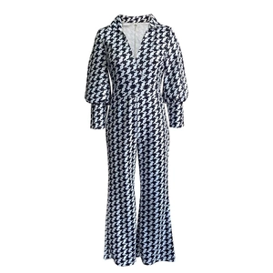 Detail of long sleeve houndstooth jumpsuit featuring a V-neck and puff sleeves