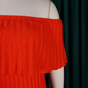Détail de la robe plissée orange à épaules dénudées avec une texture satinée sur mannequin