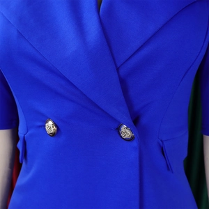 Gros plan d'un blazer bleu roi avec revers à pointe et boutons dorés en relief