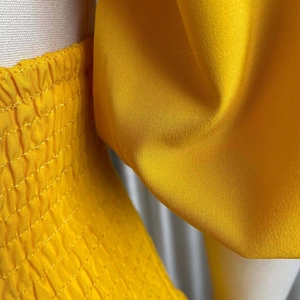 Detail of yellow smocked fabric with elastic stitching and puffed sleeve texture