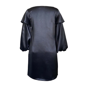Détail de la robe en satin noir avec manches bouffantes et volants sur l'épaule