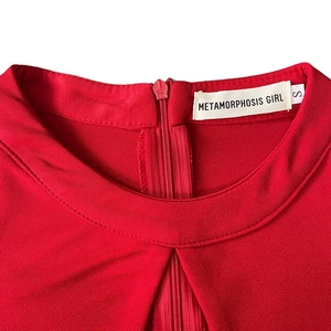 Dettaglio dello scollo dell'abito in maglia rossa con zip posteriore ed etichetta