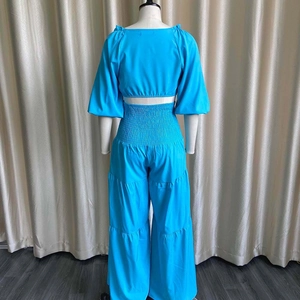 Detail view of high waist smocked waistband on cyan blue wide leg trousers and crop top set