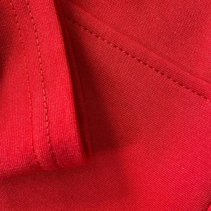 Vista macro del tessuto bandage rosso elasticizzato con doppie cuciture di precisione