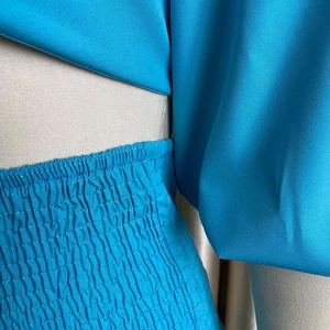 Detailed macro view of the bright blue smocked waist design and woven fabric texture