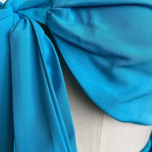 Detailed close-up of bright blue fabric showing a stylish knot design and twill texture