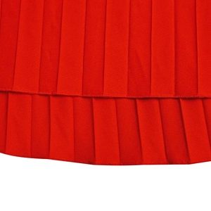 Détail en gros plan montrant la texture plissée du tissu rouge de la robe longue