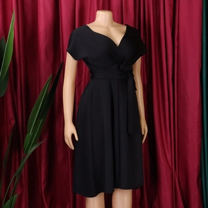 Detail view of black V-neck wrap dress with waist tie belt and pleated A-line skirt
