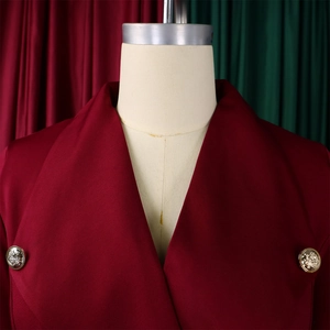 Détail d'une robe rouge vin avec large col à revers et boutons dorés tête de lion