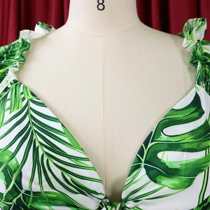 Détail de l'encolure en V à volants avec imprimé de feuilles tropicales sur tissu blanc