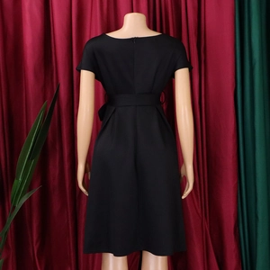 Detail view of the back of a black V-neck dress featuring a cinched waist and tie-up belt