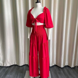 Detail of red two-piece set featuring a bow tie crop top and layered wide-leg pants