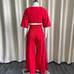 Rear view of vibrant red two-piece set featuring open-back top and high-waist ruched trousers