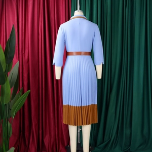 Detail eines eleganten zweifarbigen Plissee-Kleides mit braunem Lederkragen und Gürtel