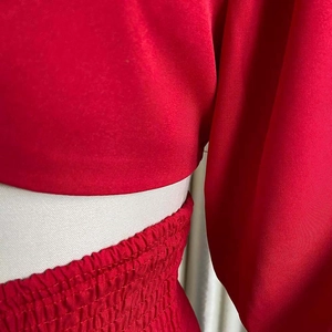 Detail of red satin two-piece set showing elastic pleated waist and textured fabric finish
