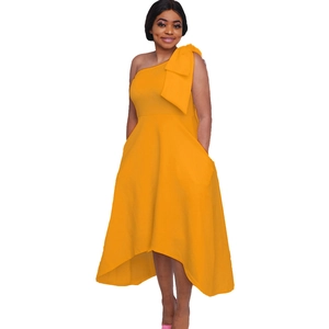 Détail de la robe asymétrique jaune à une épaule avec un grand nœud et une coupe évasée