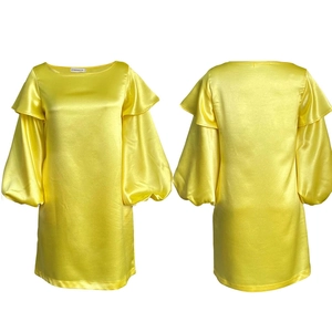 Détail du tissu en satin jaune vif et des manches bouffantes à volants de la robe