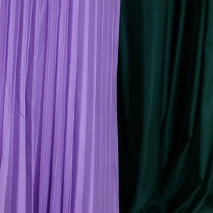 Vue détaillée de la texture du tissu plissé en violet et vert foncé au fini satiné