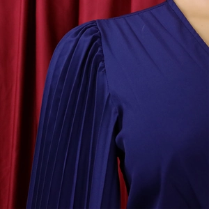 Détail des plis élégants sur l'épaule et la manche d'une robe longue bleu marine chic