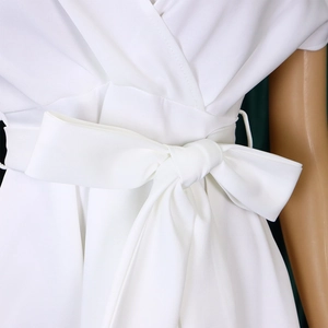 Detail of elegant white V-neck dress featuring a large waist bow and pleated texture