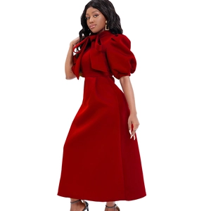 Dettaglio di abito lungo rosso con maniche a sbuffo e un elegante fiocco oversize