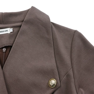 Détails de la robe marron avec col à revers, coutures et boutons métalliques à blason