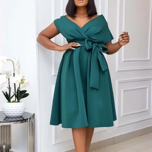 Detail of the oversized bow tie and pleated waist on a dark green V-neck dress