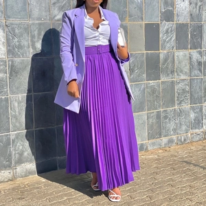 Detail of elegant pleated deep purple maxi skirt with a matching waist belt and drape