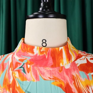 Detail of high mock neck dress featuring vibrant orange and blue abstract marble print