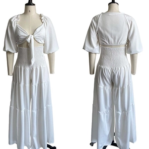 Detail view of white two-piece set featuring puff sleeve tie-up top and wide-leg trousers