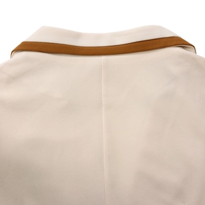 Detailansicht des cremefarbenen Blazer-Kragens mit eleganter brauner Kontrastpaspelierung