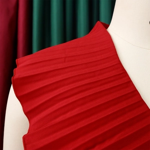 Gros plan sur le tissu plissé rouge montrant les plis verticaux et la texture de qualité