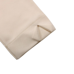 Detailaufnahme der beigen Kleidermanschette mit V-Schlitz und feiner Stoffstruktur