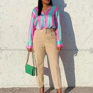 Fashionable women striped satin shirt and high waist pants with belt in street style