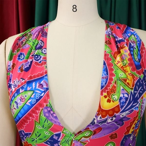 Detail of vibrant paisley floral pattern on satin halter neck jumpsuit with deep V-neck