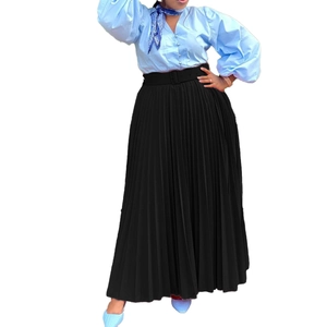 Detail of high-waist pleated black maxi skirt with matching belt and lantern sleeve blouse