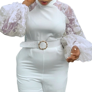 Detail of white jumpsuit featuring lace embroidered long sleeves and gold buckle belt
