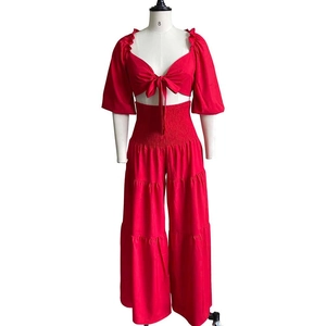 Detail of red two-piece set featuring lace-up crop top and ruched high-waisted wide-leg pants