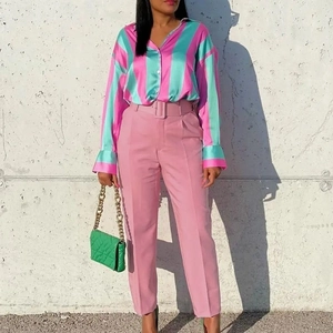 Detail of pink high-waisted suit trousers with matching belt and striped satin shirt