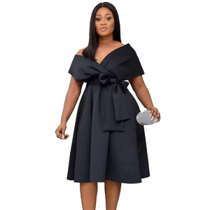 Close-up of elegant black V-neck dress featuring a large waist bow and pleated skirt
