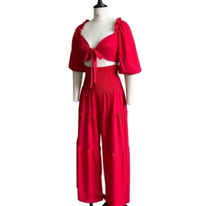 Detail of red two-piece set featuring a tie-knot crop top and pleated high-waisted pants